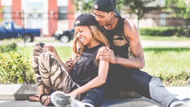Un couple assis dans l'herbe, qui rit ensemble