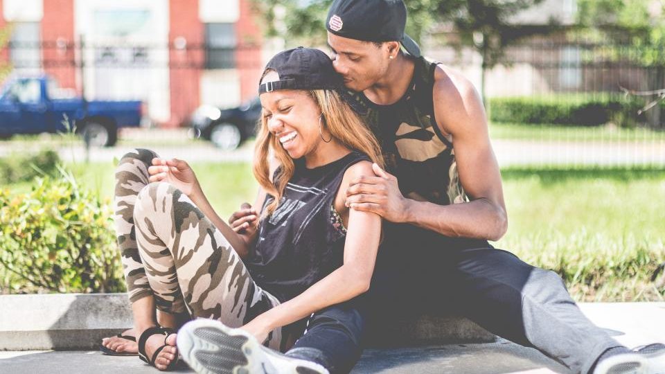Un couple assis dans l'herbe, qui rit ensemble