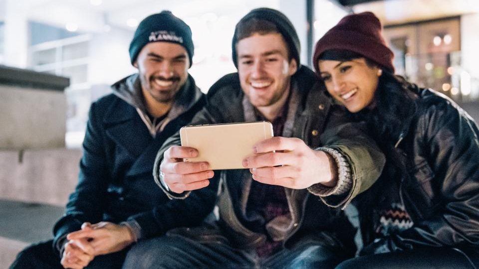 Trois amis qui jouent ensemble sur un téléphone