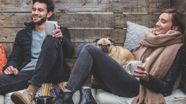 Un couple qui discute en riant, une tasse à la main