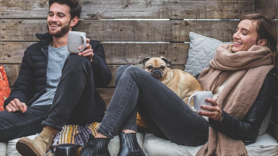Un couple qui discute en riant, une tasse à la main